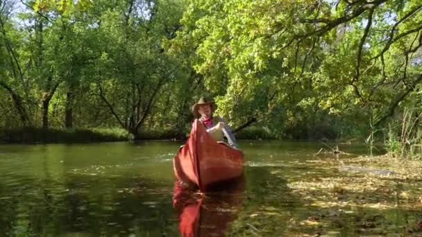 Ковбой в каноэ плавает по реке в лесу — стоковое видео