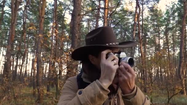 帽子を被った男が森の中で写真を撮る — ストック動画