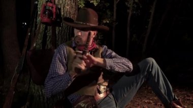 Geceleri ormanda tabancalı bir kovboy.