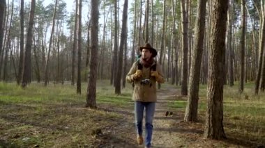 Kameralı bir sırt çantası ormanda bir patika boyunca yürüyor.