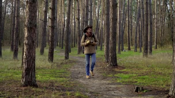 Ein Mann mit Hut und Rucksack fotografiert im Wald — Stockvideo