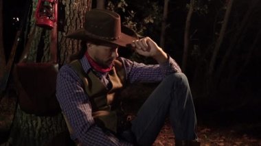 Geceleri ormanda elinde puro olan bir kovboy.