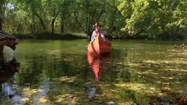 Vaquero en una canoa flota en el río en el bosque — Vídeos de Stock