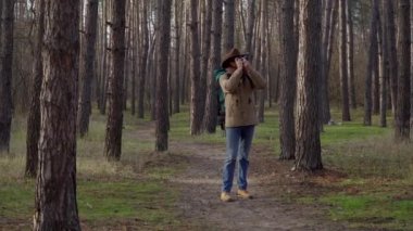Sırt çantalı bir adam ormanda fotoğraf çekiyor.