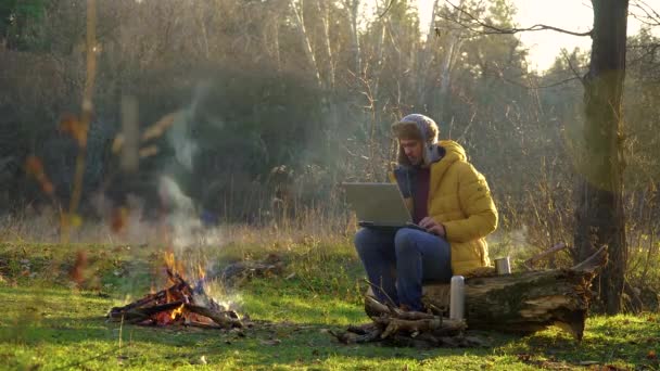 Ein junger Mann arbeitet am Laptop in der Nähe des Waldbrandes — Stockvideo