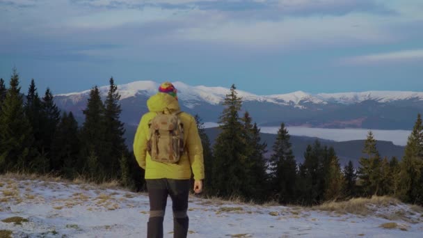 Un om cu un rucsac călătorește în munți iarna — Videoclip de stoc