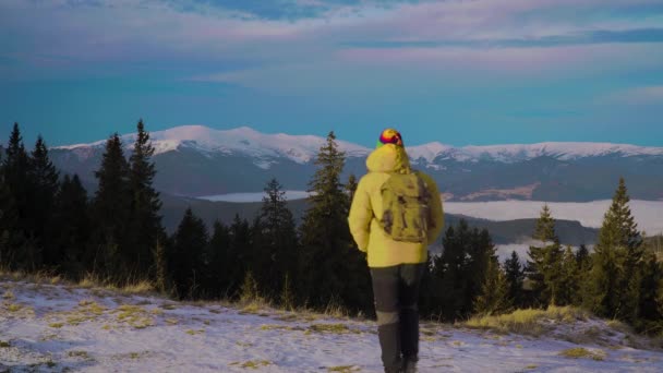 Een man met een rugzak reist in de winter door de bergen — Stockvideo