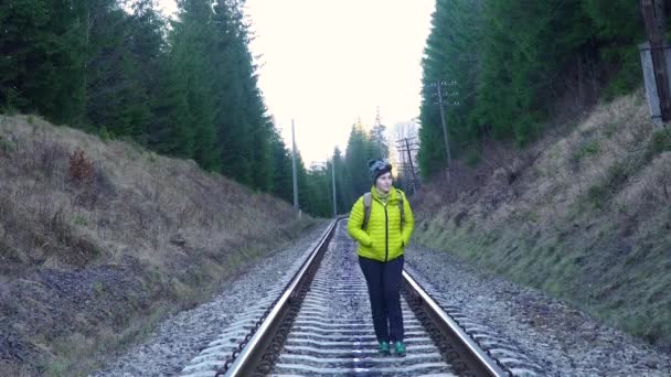 Uma mulher com uma mochila caminha na ferrovia — Vídeo de Stock