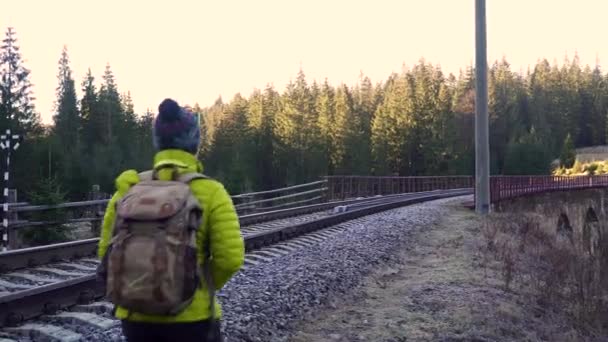 Sırt çantalı bir kadın demiryolunda yürüyor. — Stok video