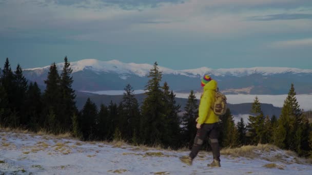 Un hombre con una mochila viaja por las montañas en invierno — Vídeos de Stock