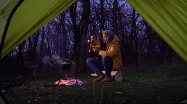 Ormandaki kamp ateşinin yanında bir adam.