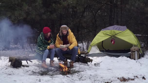 Парень и девочка читали книгу зимой в лесу — стоковое видео