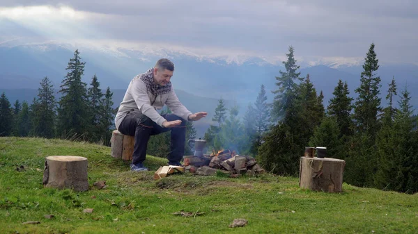 Dağlarda ateşin yanında bir adam