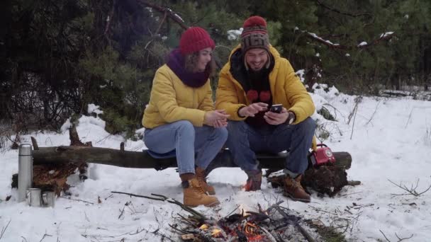 ผู้หญิงสาวและผู้ชายที่มีโทรศัพท์ในป่าฤดูหนาว — วีดีโอสต็อก