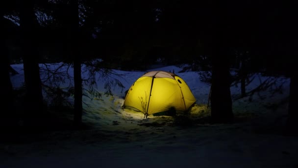 Yellow iluminated tent in winter forest — Stock Video