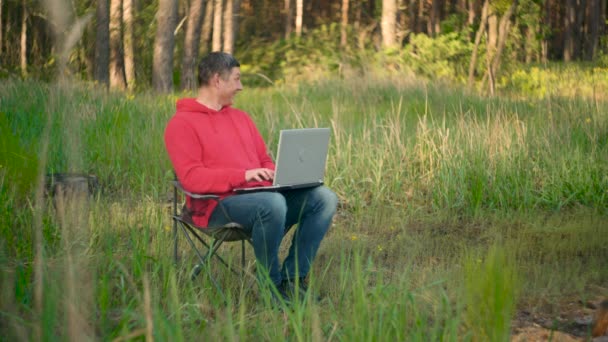 Programador engraçado trabalhando no laptop na floresta de verão — Vídeo de Stock