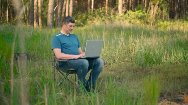 Galen programmerare arbetar på bärbar dator i sommar skog — Stockvideo