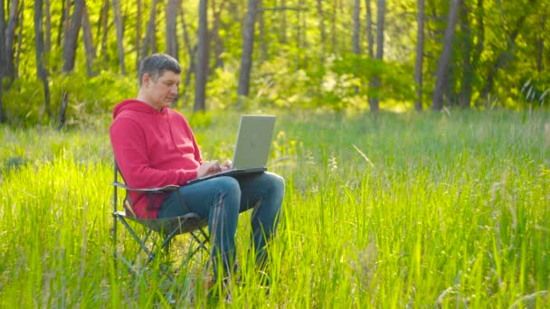 Man werkt op laptop in zomer bos — Stockvideo