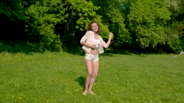한 젊은 여자가 공원의 풀밭에서 춤을 춘다 — 비디오