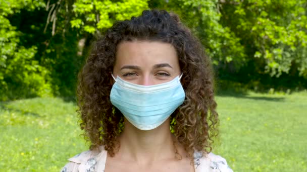 En vacker ung flicka i en medicinsk mask står — Stockvideo