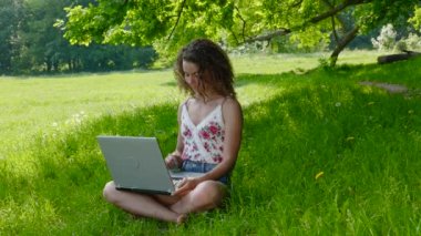 Parkta dizüstü bilgisayarda çalışan güzel bir kız öğrenci.