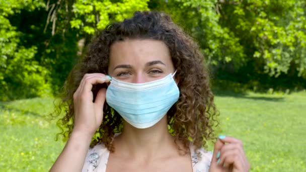 Mooi jong meisje neemt de medische masker en glimlacht — Stockvideo