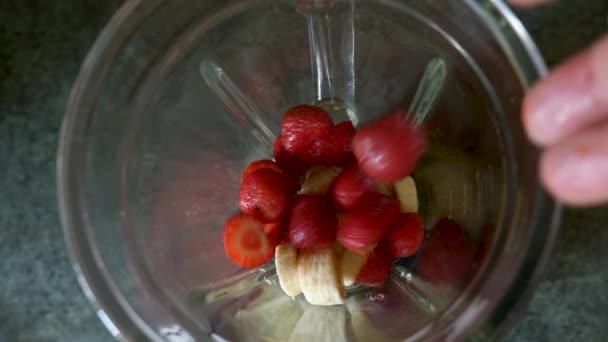 Een gezonde rauwe veganistische aardbeienbanaan soepel maken — Stockvideo