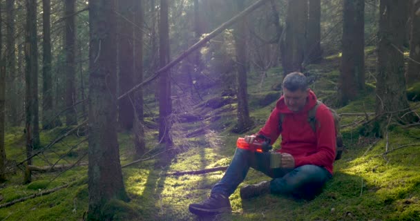 A turista srác vizet iszik és mohán pihen egy gyönyörű erdőben. — Stock videók