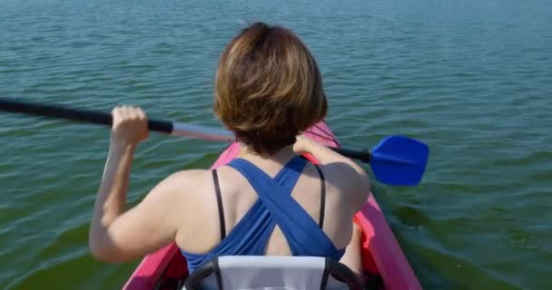 Медленное движение женщины плавает на каяке по спокойной реке — стоковое видео