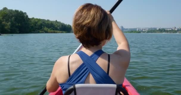 Movimiento lento de la mujer nada en un kayak en un río tranquilo — Vídeos de Stock