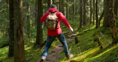 Tourist guy with a backpack runs along a trail in a beautiful forest
