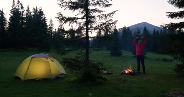 L'uomo barbuto vicino a un fuoco tra le montagne — Video Stock