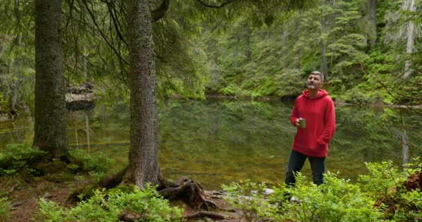 Бородач с кружкой возле горного озера — стоковое видео