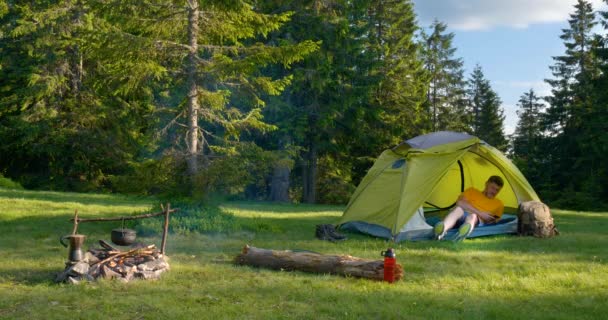 Бородач отдыхает в палатке на лесной поляне. — стоковое видео