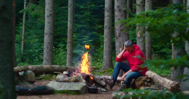 Baard mannelijke toerist in de buurt van kampvuur in het bos — Stockvideo