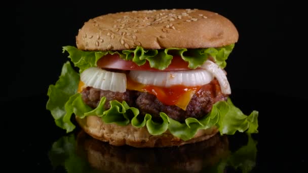 Burger de boeuf tournant sur un fond noir — Video