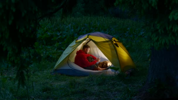 Egy férfi egy sátorban az éjszakai erdőben. — Stock videók