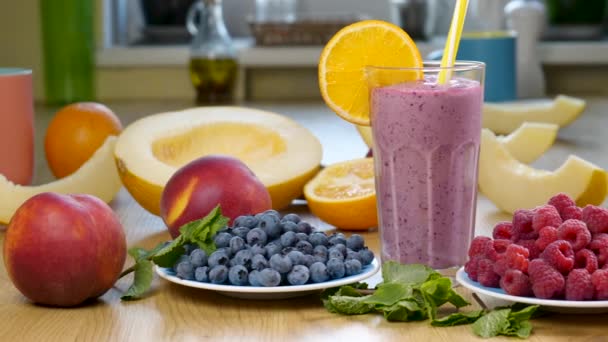 Melon, raspberry dan blueberry smoothie dalam gelas di latar belakang buah-buahan dan buah-buahan segar — Stok Video