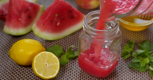 Watermeloen banaan sinaasappel Smoothie wordt gegoten in een pot op de achtergrond van vers fruit — Stockvideo