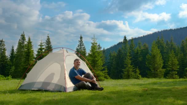 Турист відпочиває в наметі в лісовій галявині в горах — стокове відео