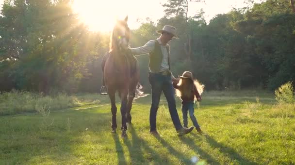 Ein Cowboy mit Pferd und seine schöne Tochter gehen auf die Weide — Stockvideo