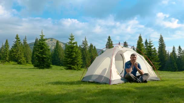 Een toerist rust in een tent in een bosgebied in de bergen — Stockvideo