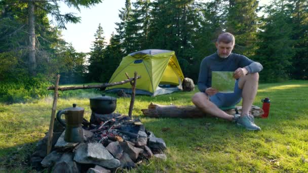 Bearded man near campfire and tent in the mountains — Stock Video