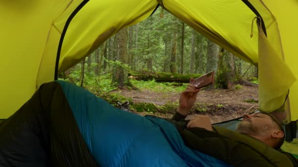 A tourist rests in a tent in a beautiful forest — Stock Video