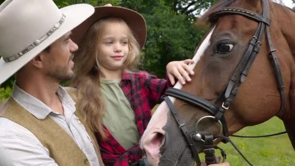 Cowboy és a lánya simogatnak egy lovat. — Stock videók