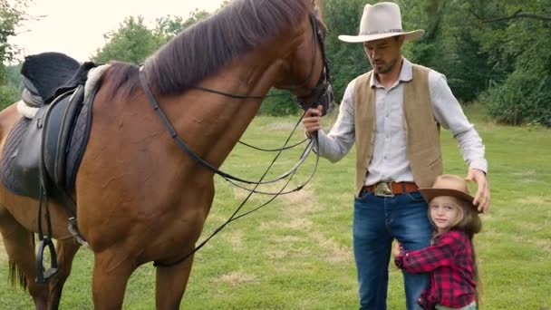 Vaquero y su hija con un caballo en el césped — Vídeo de stock