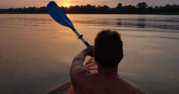 Gün batımına doğru sakin bir nehirde kano süren bir adam. — Stok video