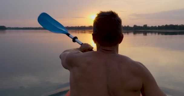 Ένας άνθρωπος καγιάκ σε ένα ήρεμο ποτάμι προς το ηλιοβασίλεμα — Αρχείο Βίντεο