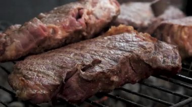 Açık ateşte ızgarada ızgara yapan sulu biftek spatula ile kızartılmış taze sığır eti ve açık havada barbekü yapan et.