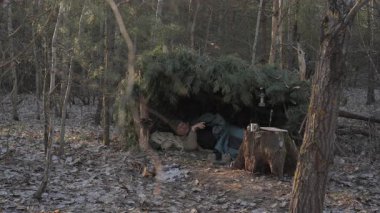 Ormandaki Pine Branch Barınağı 'nda Uyanan Adam, El yapımı çam ağacının içinde uyanıyor.